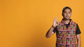 Indian man doing ok hand sign, feeling pleased, agreeing with satisfactory conclusion. Optimistic person doing okay symbol gesturing, offering positive feedback, studio background, camera A video