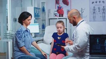 Male doctor writing child diagnostic on tablet talking with woman. Healthcare practitioner physician specialist in medicine providing health care services consultation treatment in hospital video
