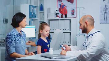 Pediatrician checking temperature and nurse writing on computer. Doctor specialist in medicine providing health care services consultation diagnostic examination treatment in hospital cabinet video