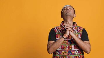 Indian man putting hands together in begging gesture, making wish, isolated over studio background. Faithful person asking for something, praying and hoping, believing in higher power, camera A video