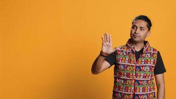 Indian man trying to stop chaotic fight using calming hand gesture to diffuse tensions, doing peaceful resolution. Reassuring person doing calm down sign gesturing, studio background, camera A video