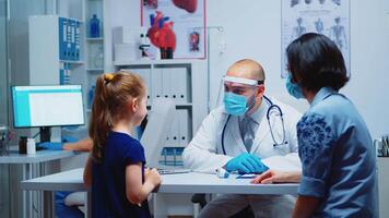 Specialist medic measuring child temperature during coronavirus pandemic. Health pediatrician specialist providing health care services consultations treatment in protective equipment for consultation video