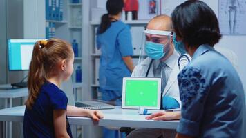 médico segurando verde tela tábua dentro médico escritório sentado em a escrivaninha. cuidados de saúde especialista com croma chave caderno isolado brincar substituição tela. fácil chaveamento remédio médico relacionado tema. video