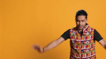 Happy indian person having fun, dancing on rhythm, enjoying leisure time. Cheerful man entertaining himself doing funky movements, isolated over studio background, camera A video