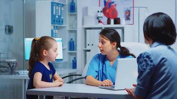 Nurse talking with child and writing girl symptoms on laptop. Physician doctor specialist in medicine providing health care services consultation diagnostic examination treatment in hospital cabinet video