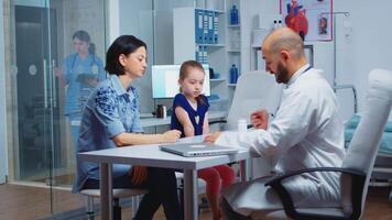 Doctor working on diagnostic examination for child health, talking and writing. Specialist in medicine providing health care services consultation diagnostic examination treatment in hospital cabinet video