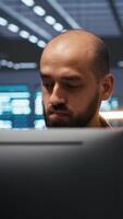 Vertical Man in server room typing code, ensuring data remains shielded from threats. Panning shot of IT technician protecting supercomputers against unauthorized access, securing system from hackers video