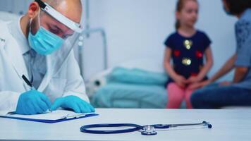 Close up of doctor wearing protective mask and gloves writing medical treatment. Physician specialist in medicine providing health care services consultation diagnostic examination in hospital cabinet video