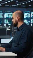 Vertical Man programming in high tech facility with server rows providing computing resources for different workloads. Admin reviewing data center supercomputers tasked with solving complex operations video