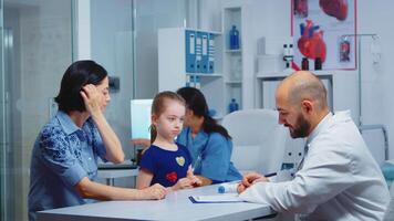 médico participación pastillas botella y escritura instrucciones mientras hablando con padre en clínica. médico, especialista en medicina Proporcionar salud cuidado servicios consulta diagnóstico tratamiento en hospital video