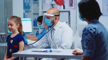 Doctor listening child breath with stethoscope wearing medical gloves. Pediatrician specialist in medicine with mask providing health care services, consultation, treatment in hospital during covid-19 video