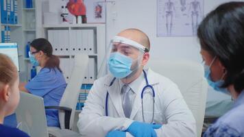 kind en dokter met bescherming masker pratend en lachend in medisch kantoor gedurende coronavirus. arts specialist in geneeskunde het verstrekken van Gezondheid zorg Diensten overleg behandeling in ziekenhuis. video