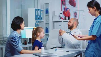 Doctor examining child in hospital using stethoscope while nurse talking with parent. Physician specialist in medicine providing health care services consultation diagnostic examination treatment video