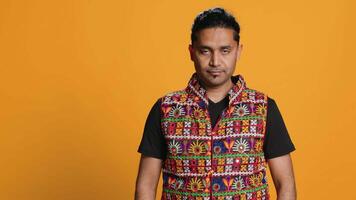 Portrait of happy man waving hand, saluting, gesturing, isolated over studio background. Cheerful indian person in traditional clothing doing greeting hand gesture, camera A video