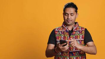 Happy man playing videogames on smartphone, celebrating after defeating foes, doing clenching hand gesture. Player swiping phone screen, thrilled about winning game, studio background, camera A video