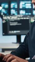 Vertical Technician coding in high tech facility with server rows providing computing resources for different workloads. Close up shot of worker overseeing supercomputers operating data video