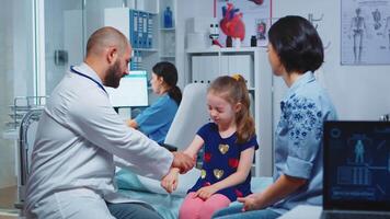 Doctor checking child injured arm and talking with mother. Healthcare practitioner physician specialist in medicine providing health care service radiographic treatment examination in hospital cabinet video