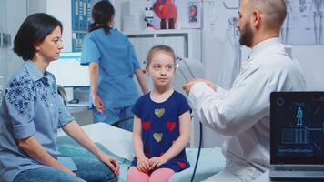 Little girl having annual medical check-up, doctor using stethoscope. Healthcare practitioner physician specialist in medicine providing health care services consultation treatment in hospital video