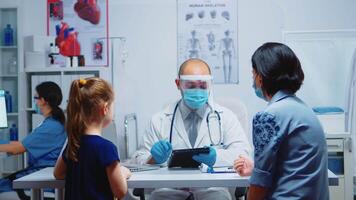 dokter controle informatie Aan tablet zittend Aan bureau vervelend bescherming masker en medisch handschoenen. beoefenaar, specialist in geneeskunde het verstrekken van Gezondheid Diensten, overleg, behandeling in ziekenhuis. video