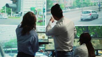 diverso equipo siguiendo ciudad tráfico en un monitor en supervisión habitación, revisando cctv satélite Radar imágenes. empleados trabajando en vigilancia y datos coleccionar, controlar centro. cámara una. video