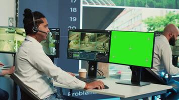 Indian operator monitors traffic next to a greenscreen on display, following surveillance footage from satellite radar cameras. Agency employee works with city CCTV system. Camera A. video