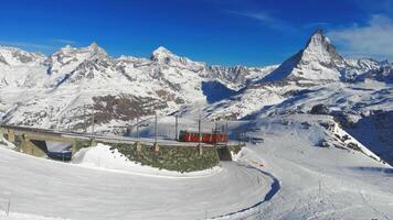 arial Disparo de un público tren transporte encima el montañas Alpes de suizo Suiza con nieve invierno montaña rango inspirador naturaleza alpinismo existencial pensamientos viaje 4k video
