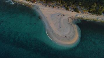 Ocean coastline with beach and sunrise or sunset tones at tropical island. Aerial view video