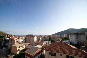 Red roofs of apartment buildings at the foot of the mountains near the sea. Budva, Montenegro photo