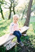 Little smiling girl sitting on a bench in the forest photo