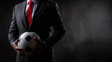 A football manager wear suit and red tie hand holding football photo