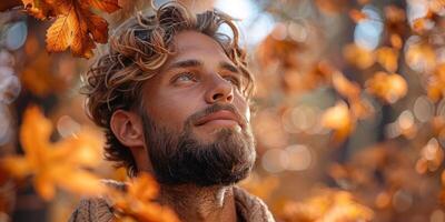 A man with a beard and mustache is smiling in a field of orange leaves photo