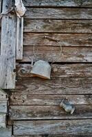 Antique teapot with a large handle and a small jug hang on an old unpainted wooden wall photo