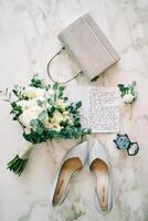 Bride shoes stand on the table next to the vows, purse, bouquet of flowers and wedding rings photo