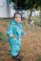 Little girl with a yellow leaf in her hand stands sideways in the garden photo