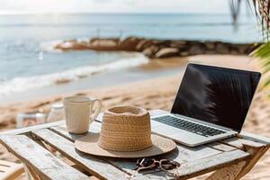 A laptop is open on a table next to a straw hat and a cup photo
