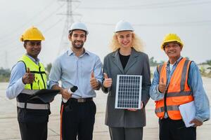 Three people are standing together, one of them holding a solar panel photo