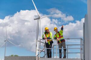 Two workers on a platform looking at a wind turbine photo