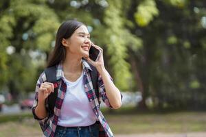 mujer es hablando en su célula teléfono mientras caminando en un parque foto