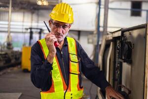 man wearing a yellow hard hat and safety vest is holding a walkie talkie photo
