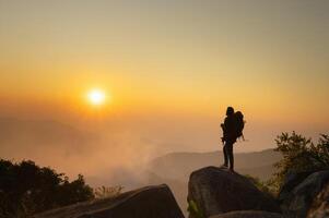 hombre es en pie en montaña arriba, mirando fuera a el puesta de sol foto