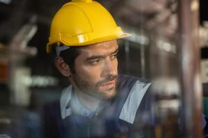 de cerca Disparo de un empleado vistiendo un difícil sombrero mientras trabajando en un industrial fábrica foto