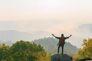 hombre es en pie en un montaña arriba, mirando fuera terminado el paisaje foto