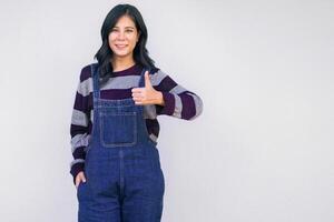 woman in blue overalls is giving a thumbs up photo