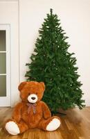 Bare artificial christmas tree with teddy bear photo