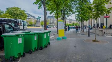 Spring cleaning on the streets of Paris, France, with green waste bins lined up near a bustling metro entrance, captured April 14th, 2024 photo