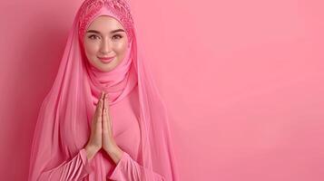 Smiling asian muslim woman making eid mubarak gesture on pastel background with text space photo