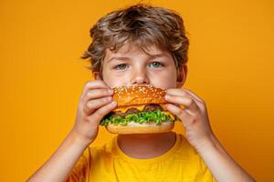 Young boy savoring hamburger against pastel backdrop with ample space for text placement photo