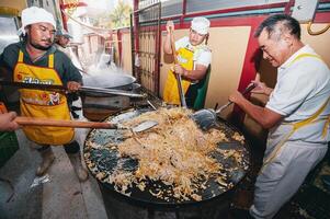 chiang mai - Tailandia octubre dieciséis, 2023 cocineros son preparando vegetariano comida en grande sartenes en el cocina a ping tao kong santuario en chiang mai provincia, Tailandia foto