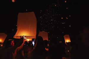 Chiang Mai - Thailand November 28, 2023  Tourists happily celebrate releasing lanterns at the Loi Krathong Yi Peng Lantern Festival according to Thai cultural traditions. photo