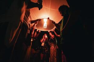 Chiang Mai - Thailand November 27, 2023. Tourists join in holding lanterns to float into the sky during the Loi Krathong Yi Peng festival to pray for good fortune. photo